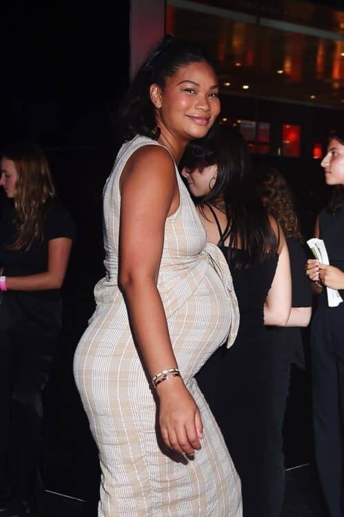 pregnant chanel iman in a beige plaid dress smiles for fans as she goes into an event