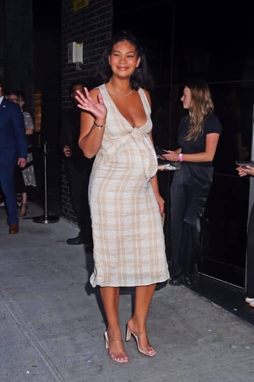 pregnant chanel iman in a beige plaid dress waves to fans as she goes into an event