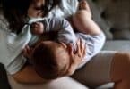 mother woman breastfeeding baby boy sitting on sofa.