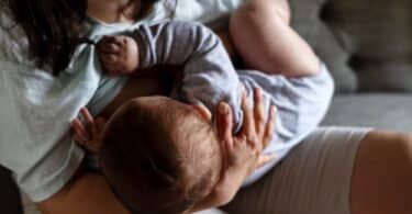 mother woman breastfeeding baby boy sitting on sofa.