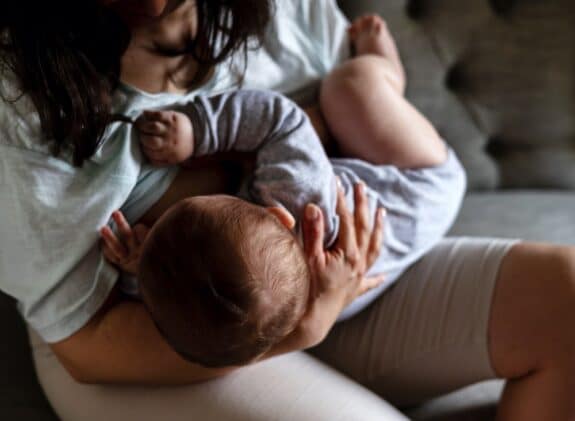 mother woman breastfeeding baby boy sitting on sofa.