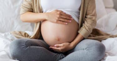 pregnant woman with bare belly sitting in bed