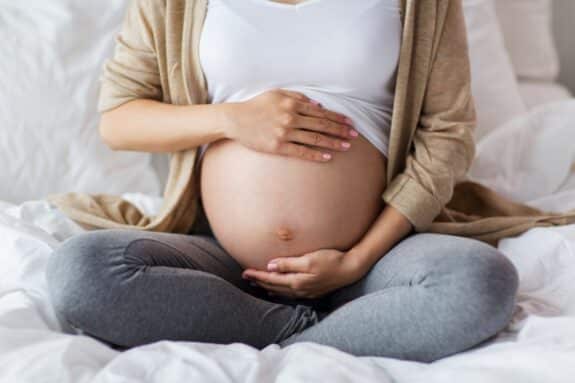 pregnant woman with bare belly sitting in bed