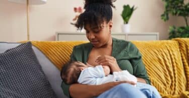 Mother and son sitting on sofa breastfeeding at home