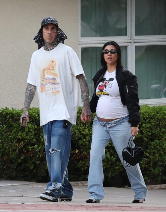 Pregnant Kourtney proudly displaying her growing belly under a vintage Mickey Mouse flipping the bird t-shirt, ripped jeans and bonnet jacket combo with Travis Barker