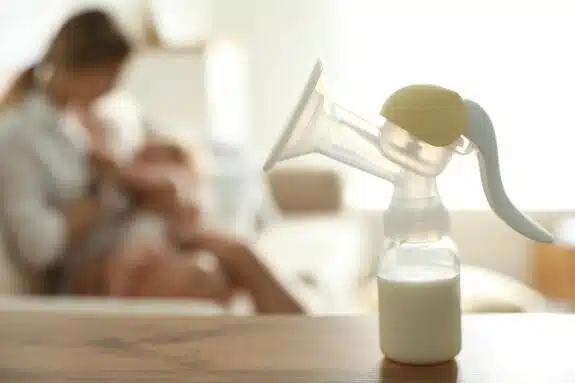 breast feeding mom with breast pump in forefront