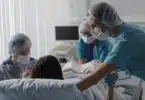 Woman giving birth with husband holds her hand in support and obstetricians assisting
