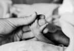 parent holds the tiny hand of their premature baby