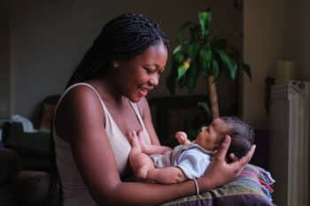 Happy mother with her baby on arms at home