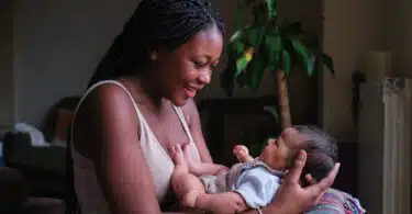 Happy mother with her baby on arms at home