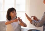 Mother daughter sitting on couch nonverbal communicating with sign language