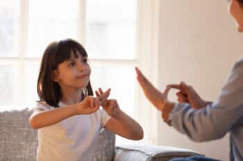 Mother daughter sitting on couch nonverbal communicating with sign language