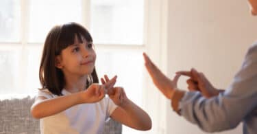 Mother daughter sitting on couch nonverbal communicating with sign language