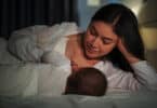 Mother is breastfeeding a infant baby while lying and sleeping on bed at night