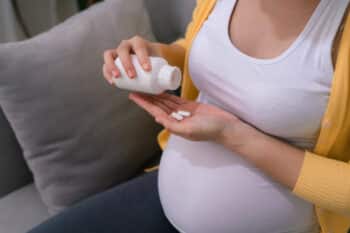 Pregnant mom on sofa taking medicine