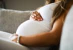 Close-up of pregnant woman sitting in sofa with her hands at belly