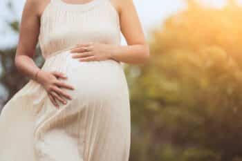 Pregnant woman touching her big belly and walking in the park