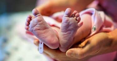 Newborn baby feet and hands of the mother