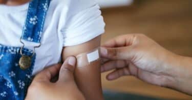 woman putting a bandaid on her child's arm