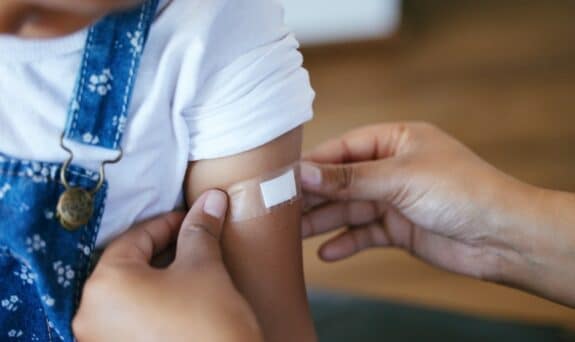 woman putting a bandaid on her child's arm