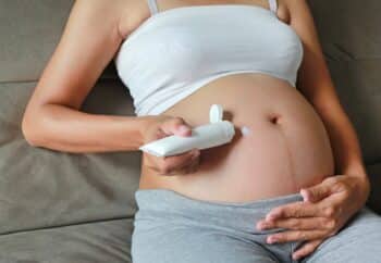 Pregnant woman putting cream on her belly
