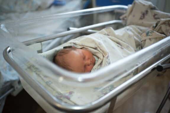 Newborn baby sleeps in a transparent plastic cradle