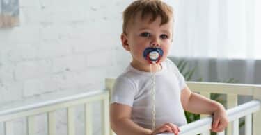 baby boy with pacifier in baby crib