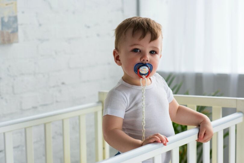 baby boy with pacifier in baby crib
