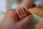 Newborn little hand hold by adult hand