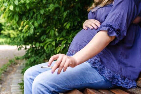 Pregnant Woman Smoking Cigarette Outdoor in park