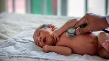 doctor uses stethoscope to check newborn baby health