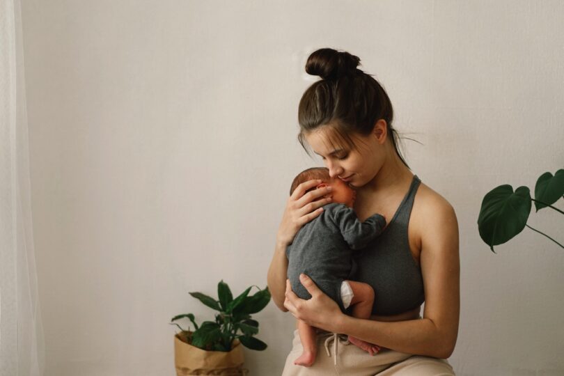 Mother holds and hugs her newborn baby son at home
