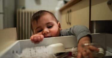 Curious baby exploring kitchen drawer