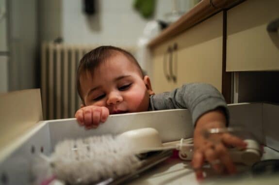 Curious baby exploring kitchen drawer