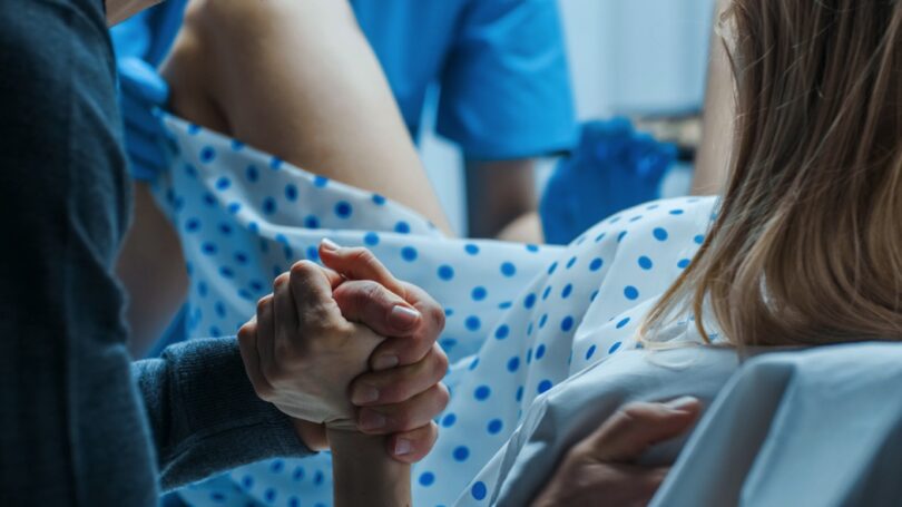 Woman Giving Birth, Husband Holds Her Hand in Support, Obstetricians Assisting