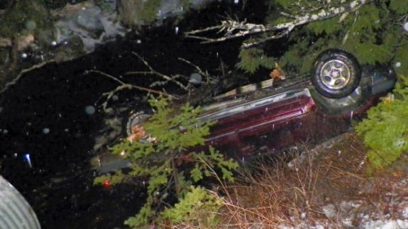 An SUV rests upside down in water alongside Route 6 in Kossuth Township, Maine