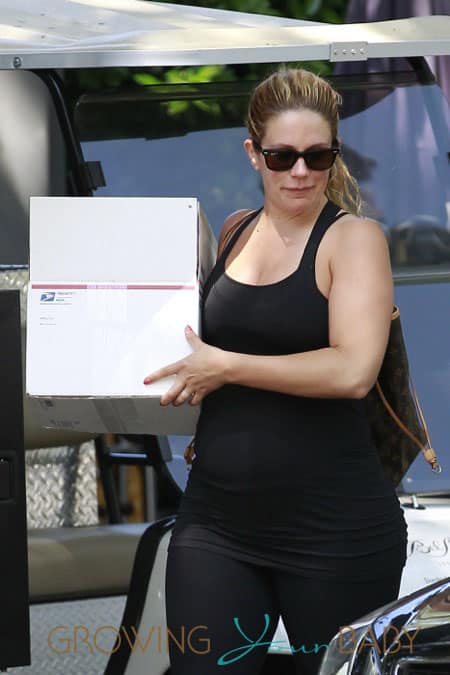 Cacee Cobb shows off her growing baby bump in a black tank top and workout leggings as she carries a package into the Bel-Air Hotel in Los Angeles